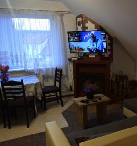 uma sala de estar com uma televisão de ecrã plano e uma mesa em Apartament Czos Kominek Premium em Mrągowo