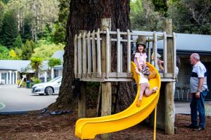 a woman sitting on a slide on a playground at Ripple Rotorua in Rotorua