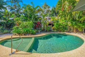 una piscina frente a una casa con árboles en Absolute beachfront, heart of Port Douglas - 24 S, en Port Douglas