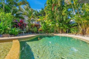 una piscina en un complejo con palmeras en Absolute beachfront, heart of Port Douglas - 24 S, en Port Douglas