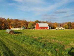 a large field with a red barn and hay bales at The Stable at Windmill Ridge Farm in Fredonia