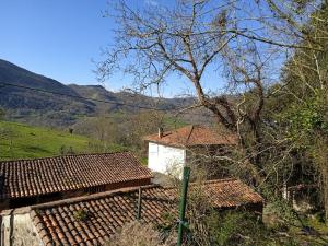 a building with red tile roofs with mountains in the background at Casa Molily in Llanes