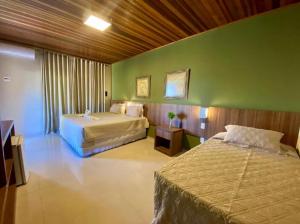 a bedroom with two beds and a green wall at Águas do Manso Hotel E Marina in Chapada dos Guimarães