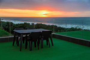 a table and chairs on a balcony with the sunset at Qophelo Sea Views in La Mercy