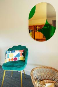 una sedia verde in una stanza con specchio di Cheerful Family Friendly Cottage Patio with BBQ a Canterbury