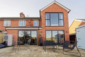 un gruppo di sedie seduti su un patio di fronte a una casa di Cheerful Family Friendly Cottage Patio with BBQ a Canterbury