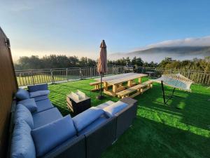a patio with a couch and a picnic table and an umbrella at Modern Catskill House & Lake NY with hot tube on the roof in Stamford
