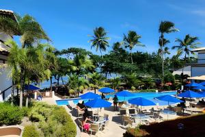 a view of the pool at a resort with blue umbrellas at Lindo apto no Condomínio Enseada Praia do Forte in Mata de Sao Joao