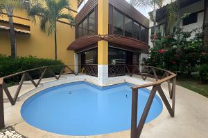 a house with a swimming pool in front of it at Lindo apto no Condomínio Enseada Praia do Forte in Mata de Sao Joao
