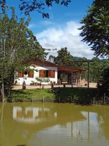 een huis met een vijver ervoor bij Sítio do Dindinho - Aiurê in Grão Pará