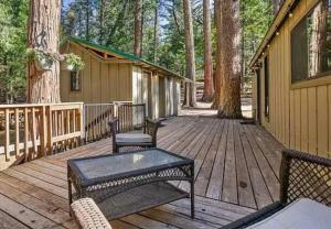 a wooden deck with two chairs and a table at Cozy Cabin Retreat in Ponderosa