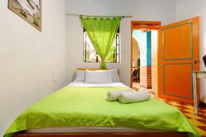 a bedroom with a green bed with two towels on it at Ding-Dong Hostel in Cali