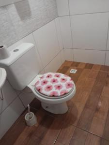 a bathroom with a toilet with a pink cover at Chácara jerivá in Boituva