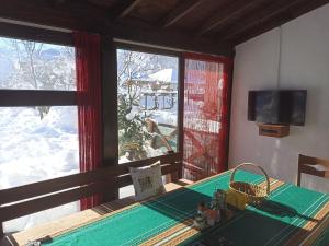 Cette chambre dispose d'une table et d'une fenêtre avec de la neige à l'extérieur. dans l'établissement Къща Ралица, à Chakalarovo