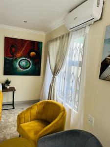 a living room with a yellow chair and a window at Chimas Guest House in Musina