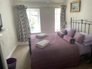 a bedroom with a bed with purple sheets and pillows at The Plover in Blakeney