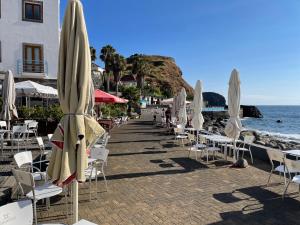 a beach with chairs and umbrellas and the ocean at Sea Breeze Studios in Porto da Cruz