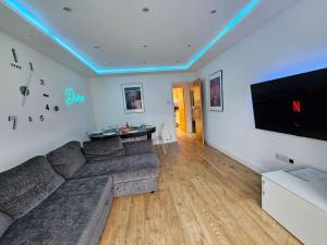 ein Wohnzimmer mit Couch und Flachbildfernseher in der Unterkunft Neon Heights 2 bed Luton town centre in Luton