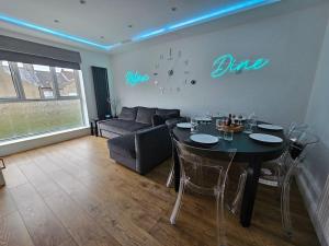 ein Wohnzimmer mit Tisch und Couch in der Unterkunft Neon Heights 2 bed Luton town centre in Luton