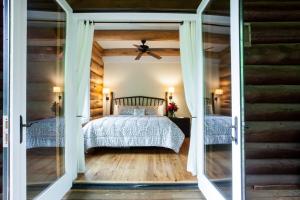 - une chambre avec un lit et un ventilateur de plafond dans l'établissement Black Mountain Log Cabin Secluded, Pet-friendly 3BD with Hot Tub & Views!, à Black Mountain