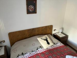 a bed with a wooden headboard and a picture on the wall at Affittacamere Iragidor in Cortina dʼAmpezzo