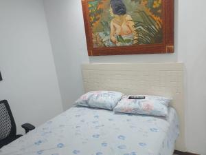 a bedroom with a bed with a painting on the wall at Apartamento frente mar - Barra da Tijuca in Rio de Janeiro
