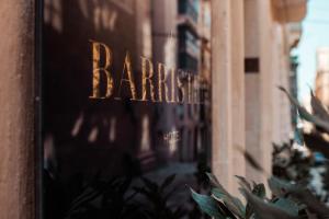 a shop window with the name of a barbershop at The Barrister Hotel in Valletta