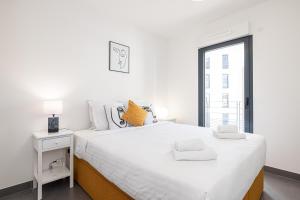 a white bedroom with a large bed and a window at Queen Riviera : climatisation, parking, terrasse in Menton