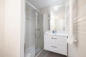 a white bathroom with a shower and a sink at Queen Riviera : climatisation, parking, terrasse in Menton