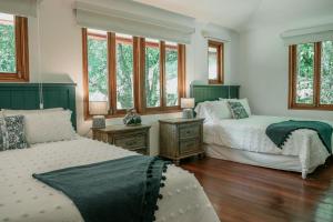 a bedroom with two beds and windows and wooden floors at La Perezosa in Cerro Azul