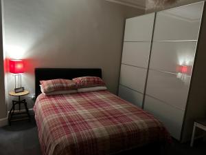 um quarto com uma cama com um edredão xadrez em The Old Post Office Double Room (town centre) em Carnoustie