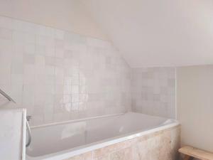 uma banheira branca numa casa de banho com azulejos brancos em Maison Béganne - Nature & Charme em Béganne