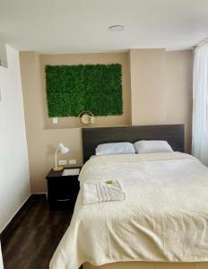 um quarto com uma cama grande e uma pintura verde em TRÉBOL GOLDEN HOTEL em Ipiales