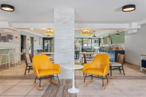 a lobby with yellow chairs and a table and a counter at Spark by Hilton Hilton Head Island in Hilton Head Island