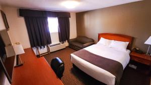 a hotel room with a bed and a chair at Travelodge by Wyndham Valleyview AB in Valleyview