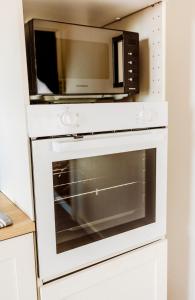 La cocina está equipada con microondas sobre un horno blanco. en A1, en Évaux-les-Bains