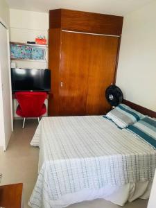 1 dormitorio con 1 cama y escritorio con silla roja en Flat na praia da Costa!, en Vila Velha