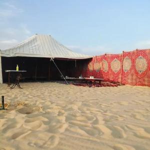 namiot w piasku ze stołem przed nim w obiekcie Five oasis desert camp w mieście Az Zabū