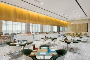 a restaurant with tables and chairs and yellow curtains at Le Meridien Shenyang Heping in Shenyang