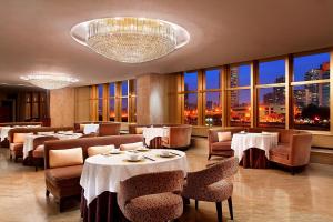 uma sala de jantar com mesas, cadeiras e janelas em Sheraton Xiamen Hotel em Xiamen