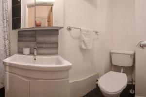 a white bathroom with a sink and a toilet at Top Hat Luton flat free parking in Luton