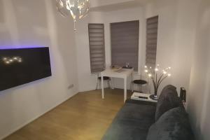 a living room with a couch and a desk with a tv at Top Hat Luton flat free parking in Luton