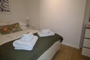 a room with a bed with towels on it at Top Hat Luton flat free parking in Luton