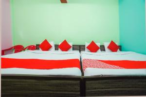 a bedroom with two beds with red and white pillows at OYO 66014 The Rudralok Hotel in Gopeshwar