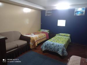 Habitación pequeña con 2 camas y sofá en Hotel RITZOR, en Latacunga