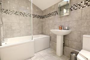 a bathroom with a sink and a tub and a toilet at The Old Corn Store Rural Escape Farmstay Barn in Norwich