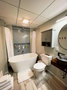 a bathroom with a tub and a toilet and a sink at Finn's Hideaway -Modern family river home in Keokuk