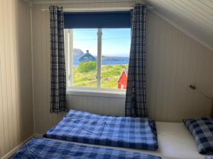 Un dormitorio con una cama y una ventana con vistas. en Koselig Hytte i Nykvåg, en Nykvåg
