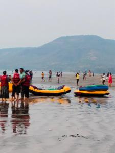 a group of people standing on a beach with canoes at Om Laxmi Narayan Homestay in Diveagar
