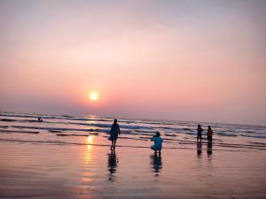 a group of people walking on the beach at sunset at Om Laxmi Narayan Homestay in Diveagar